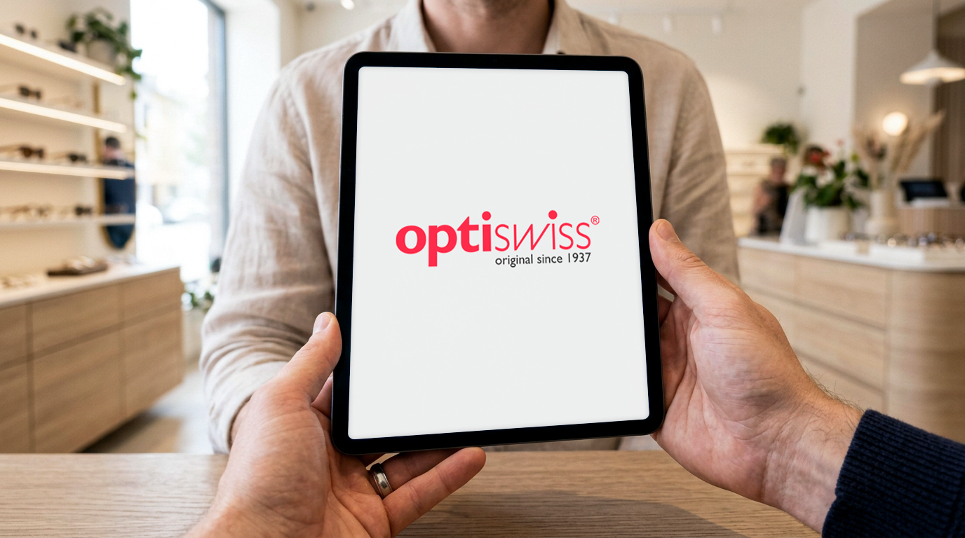 Tablet med OptiSwiss-logo holdes frem i en moderne optikerbutik